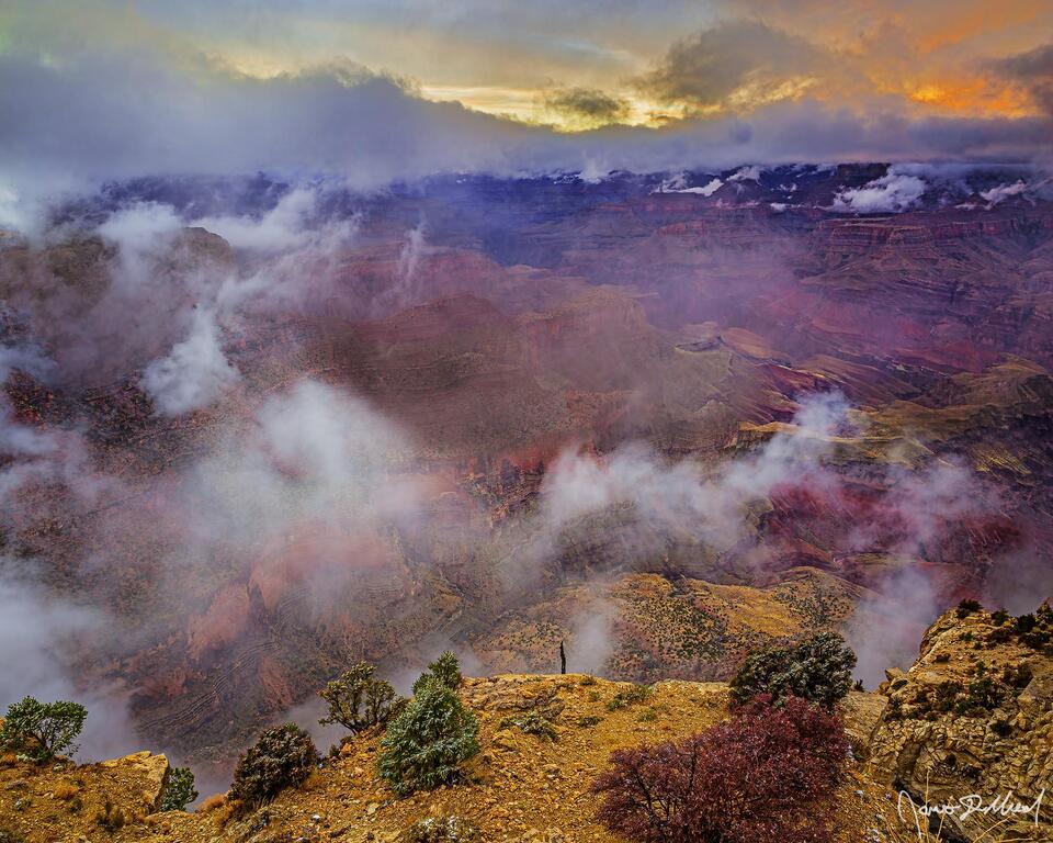 A partial thermal inversion begins to form in the Grand Canyon as the clouds in the skies above light at sunset above the inner canyon and the Colorado River.