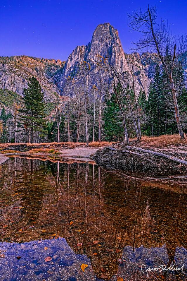Alpenglow hangs on during Nautical Twilight, illuminating the top of Sentinel Rock and the surrounding cliffs as the stars begin to come out high above Yosemite