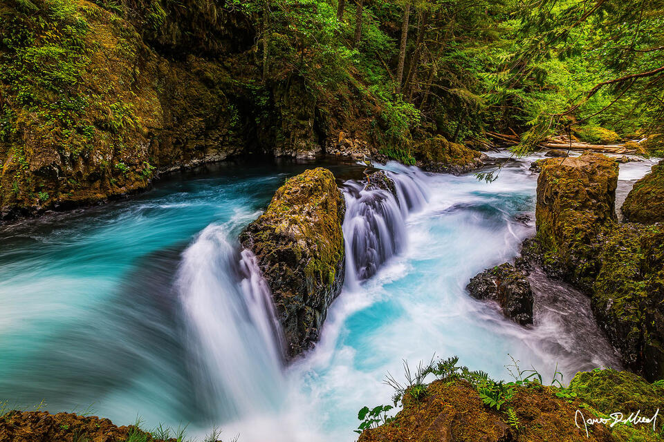 Little White Salmon River, Washington. Turquoise waters spill over the ledge and continues downstream through the narrow forest gorge.