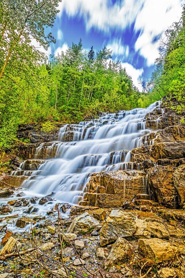 Silver Staircase Falls gracefully cascades 40 feet down the cliffs in Glacier National Park, paint the tiered cliffs in silver paint made of water.
