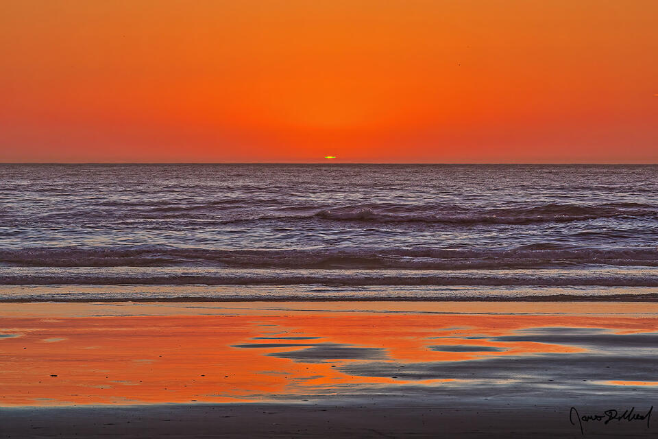 A mock-mirage green flash at sunset over the Pacific Ocean. A thermal inversion layer forms a layer of air which blocks the last part of the sun's image.