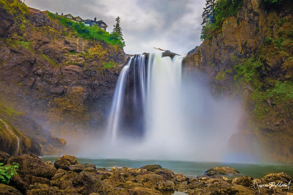 Mist flies up as the waters of the Snoqualmie River crash against the rocks as Snoqualmie Falls drops 268 feet over the cliffs and into a pool water.