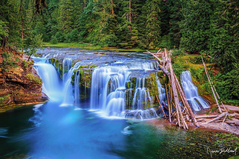 Water flows over Lower Lewis River Falls, creating a series of small terraces as it flows over the rocky cliffs of the Lewis River.