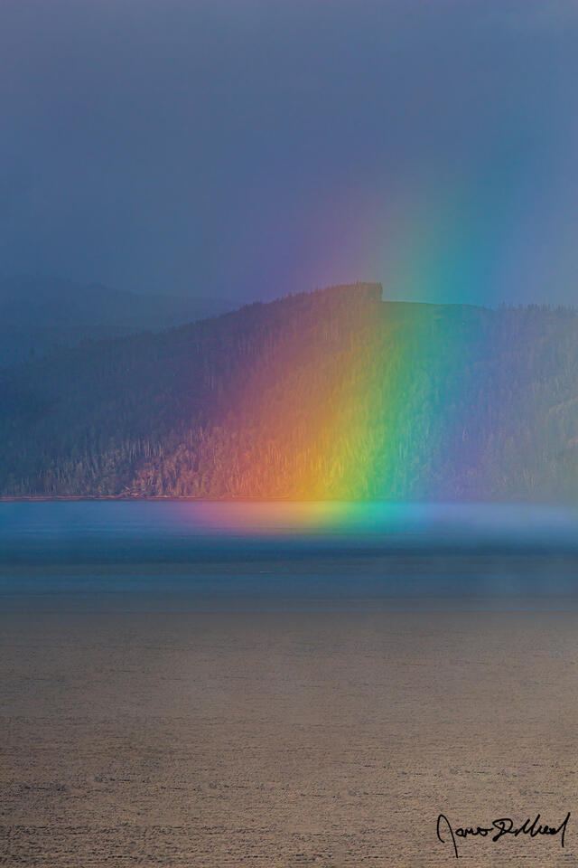 A rainbow shines through a parting storm across the mouth of the Columbia River in Astoria, Oregon on the Oregon Coast.