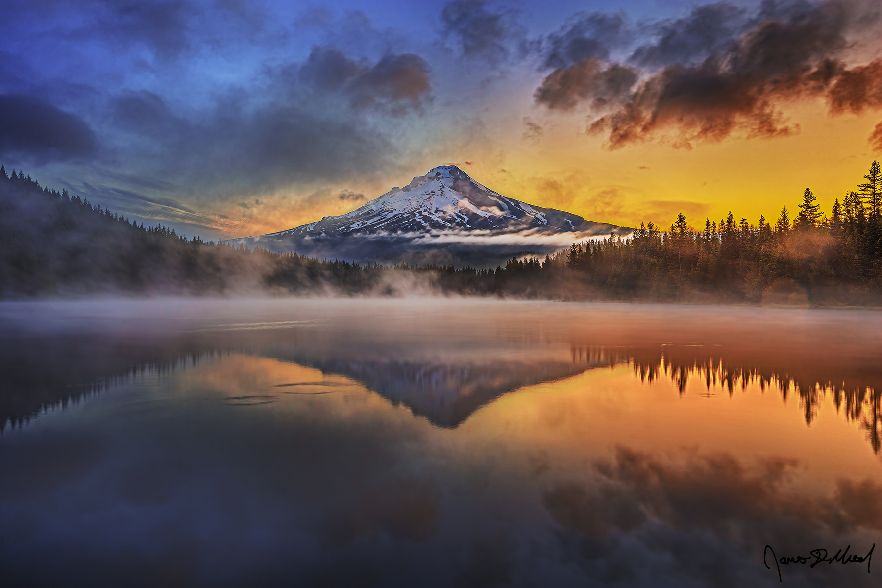 A reflection of Mount Hood in the waters of Trillium Lake at sunrise as fog rises from the lake in the Mount Hood National Forest of Oregon.