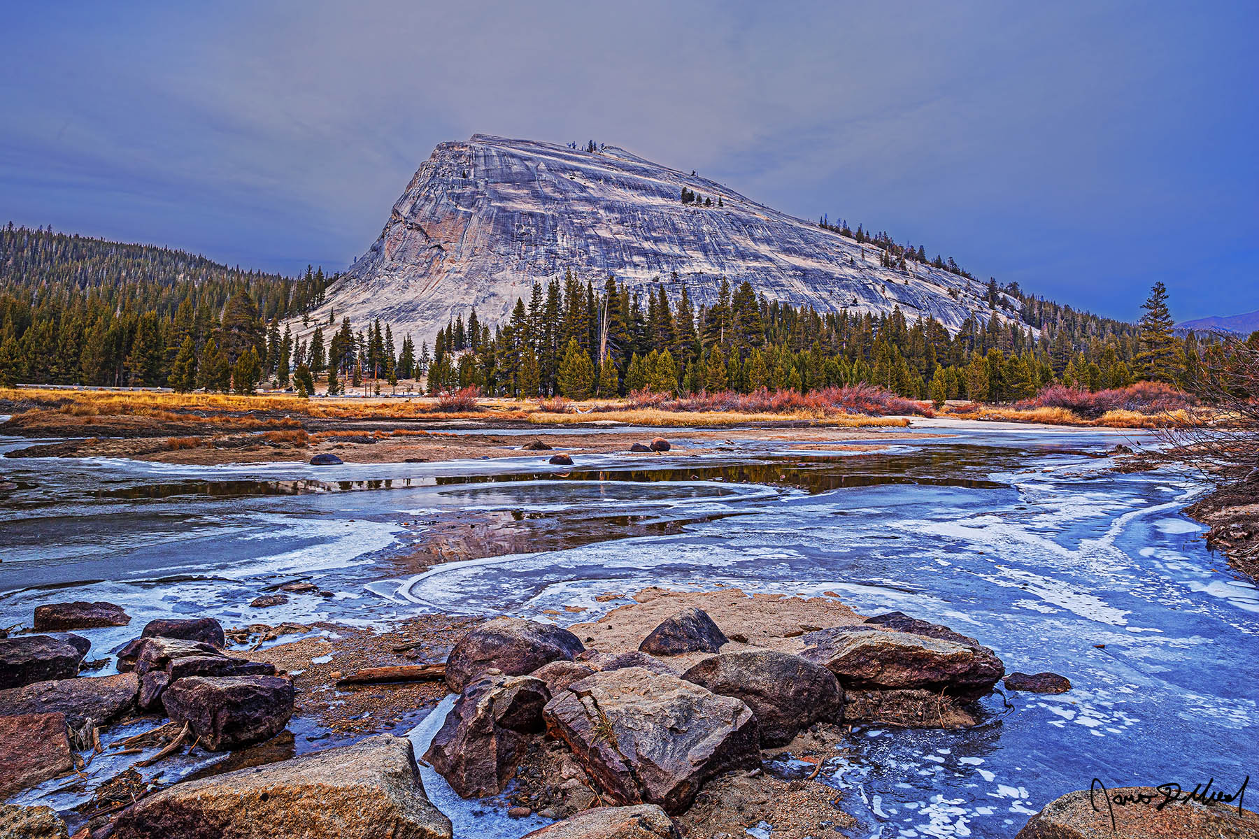 Fade to Winter The Tuolumne River freezes over after a long cold spell as the first storm of winter nears. Lembert Dome reflects in the small patches of unfrozen water.