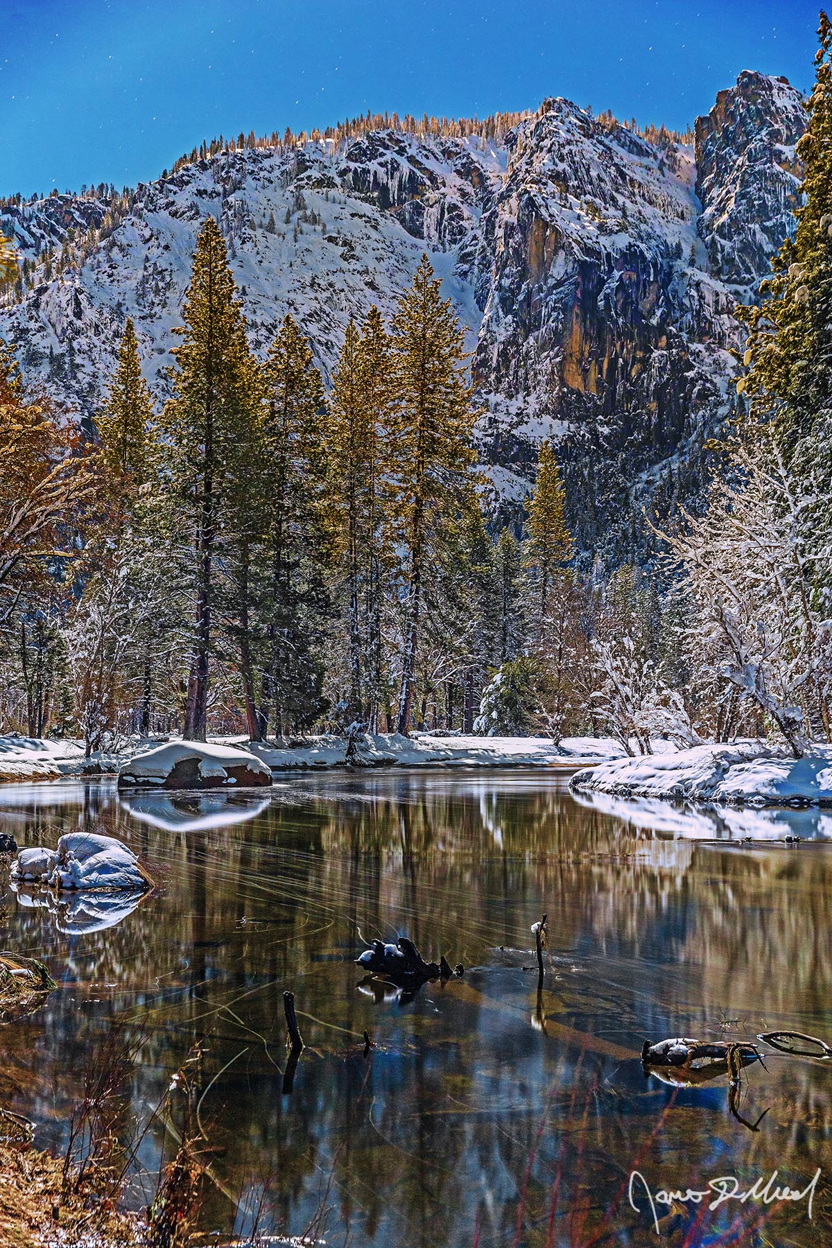 Midnight Stillness Moonlight illuminates the snow covered granite cliffs above Yosemite Valley in the winter as the still, clear waters of the Merced River reflect the trees .