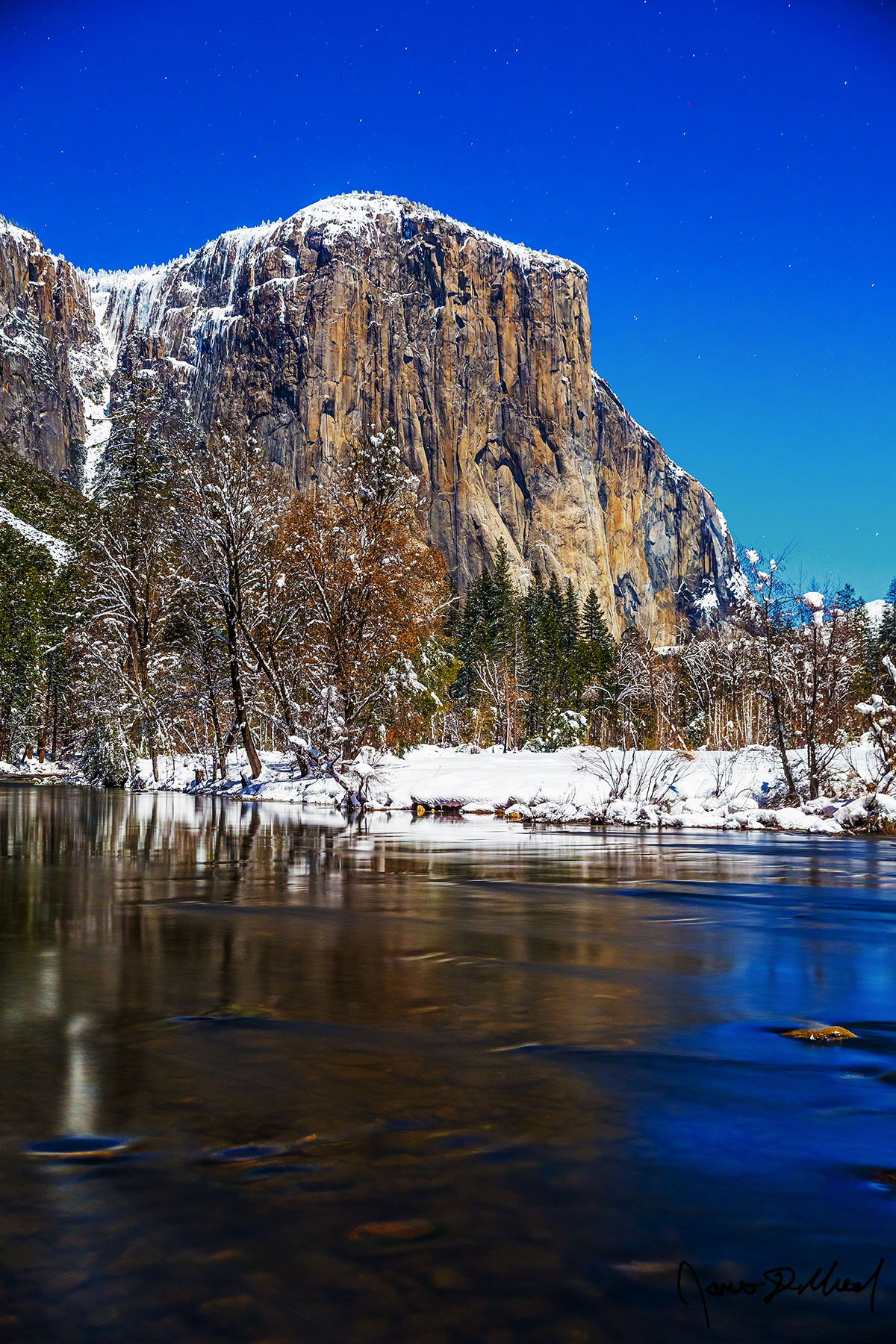 Night Rise Moonlight illuminates Yosemite Valley, El Capitan, and the Merced River in the winter as snow blankets the valley on a cold winter night.