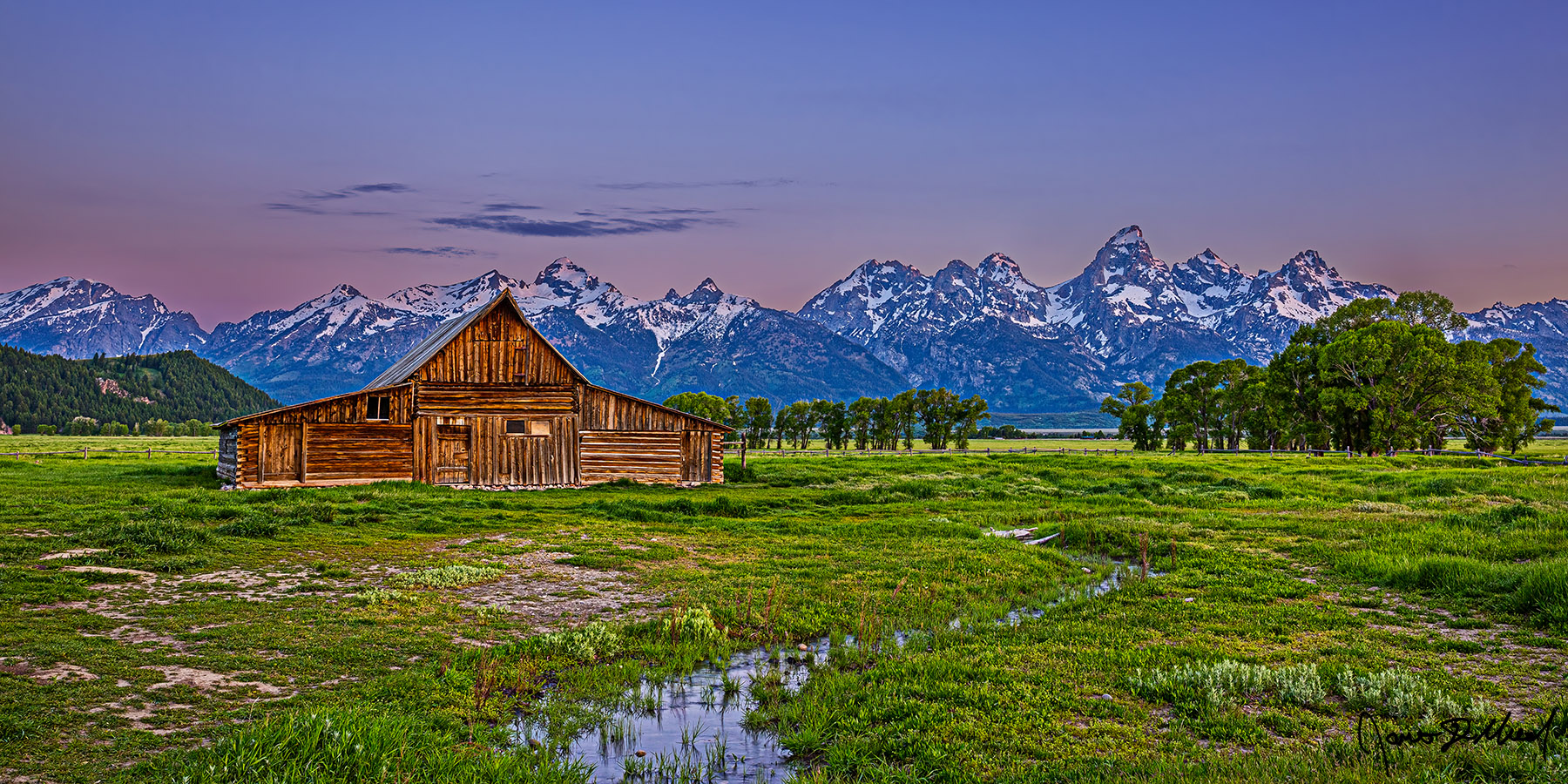 Time Without End - Alpenglow Sunrise on the TA Moulton Barn, the Teton Range and the Cathedral Group Alpenglow begins to illuminate the top of the peaks of the Grand Teton Range as a small creek runs through the green meadow in front of the TA Moulton Barn.