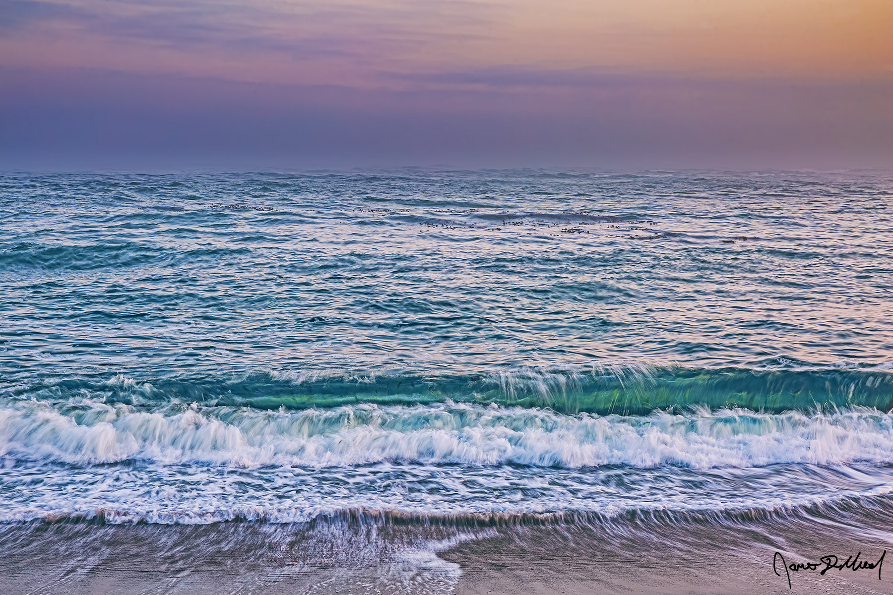 Lost at Sea Emerald Waves in the Pacific Ocean roll towards the shore as sunrise brings the soft colors of the Belt of Venus to the skies on the horizon.