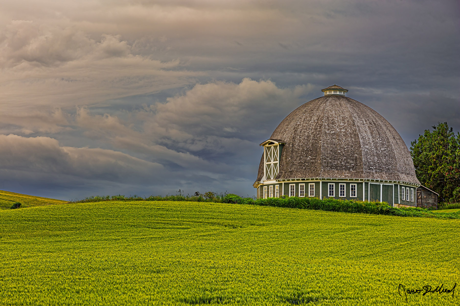 Idyllic Menacing clouds at sunrise line the skies above the 12 sided Leonard Round Barn (T.A. Leonard Barn) in the Palouse near Pullman Washington and Moscow Idaho.