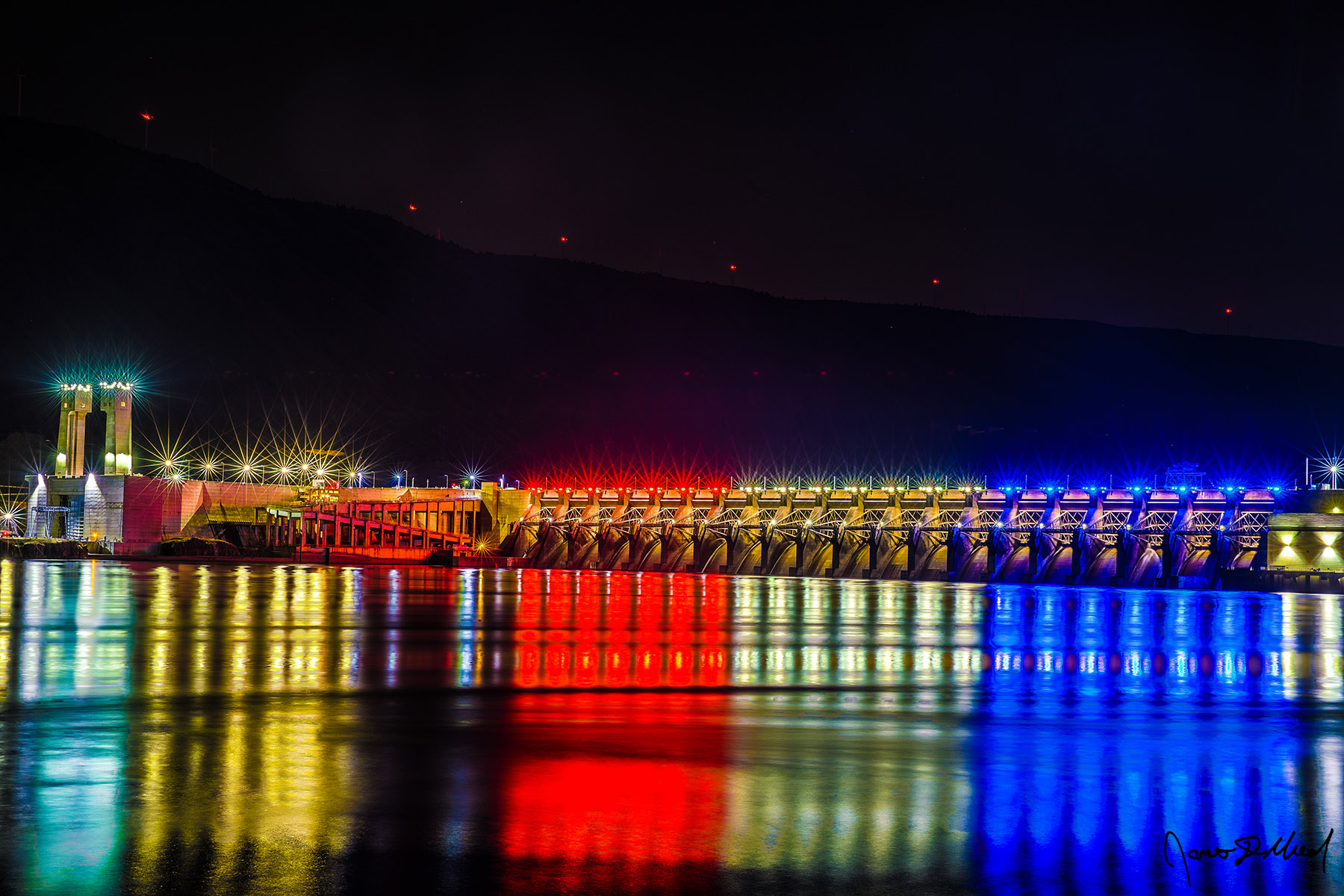 Red, White and Blue - John Day Dam Reflection in the Columbia River at Night, Oregon Red, white and blue lights of the John Day Dam reflect off the waters of the Columbia River at night as the red lights of the Windmills line the slopes above.
