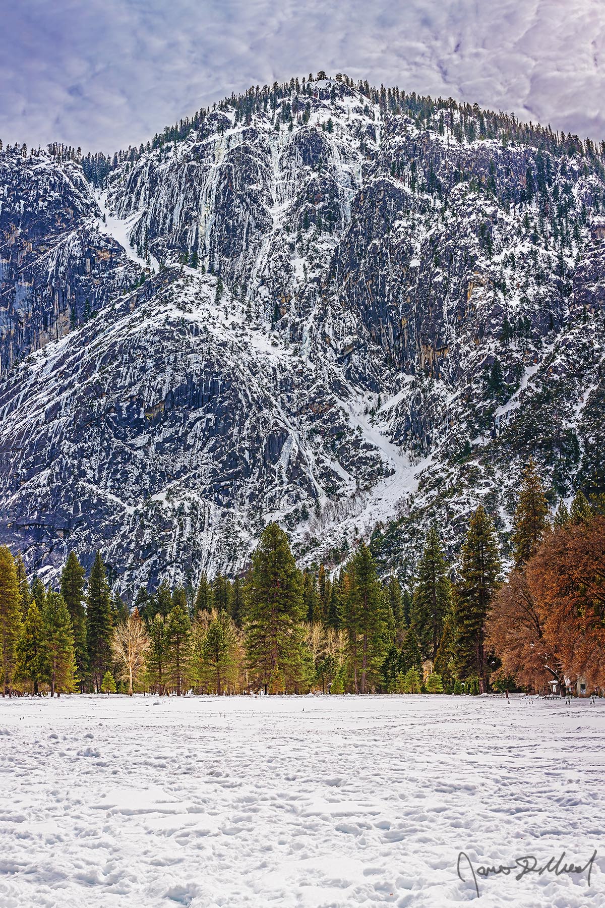 Patchwork Snow and ice cover the slopes and sheer granite rock faces in a frozen patchwork high above snow covered Ahwahnee Meadow and Yosemite Valley.