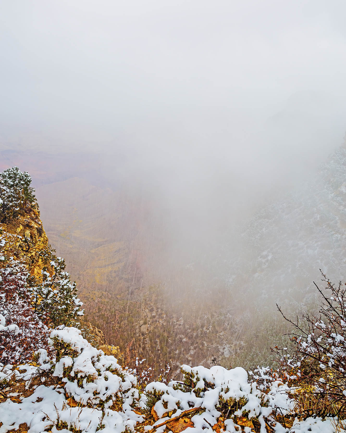 Obscured Snow lines the top of the Grand Canyon during a winter storm as a temperature inversion begins to form in the canyon below.