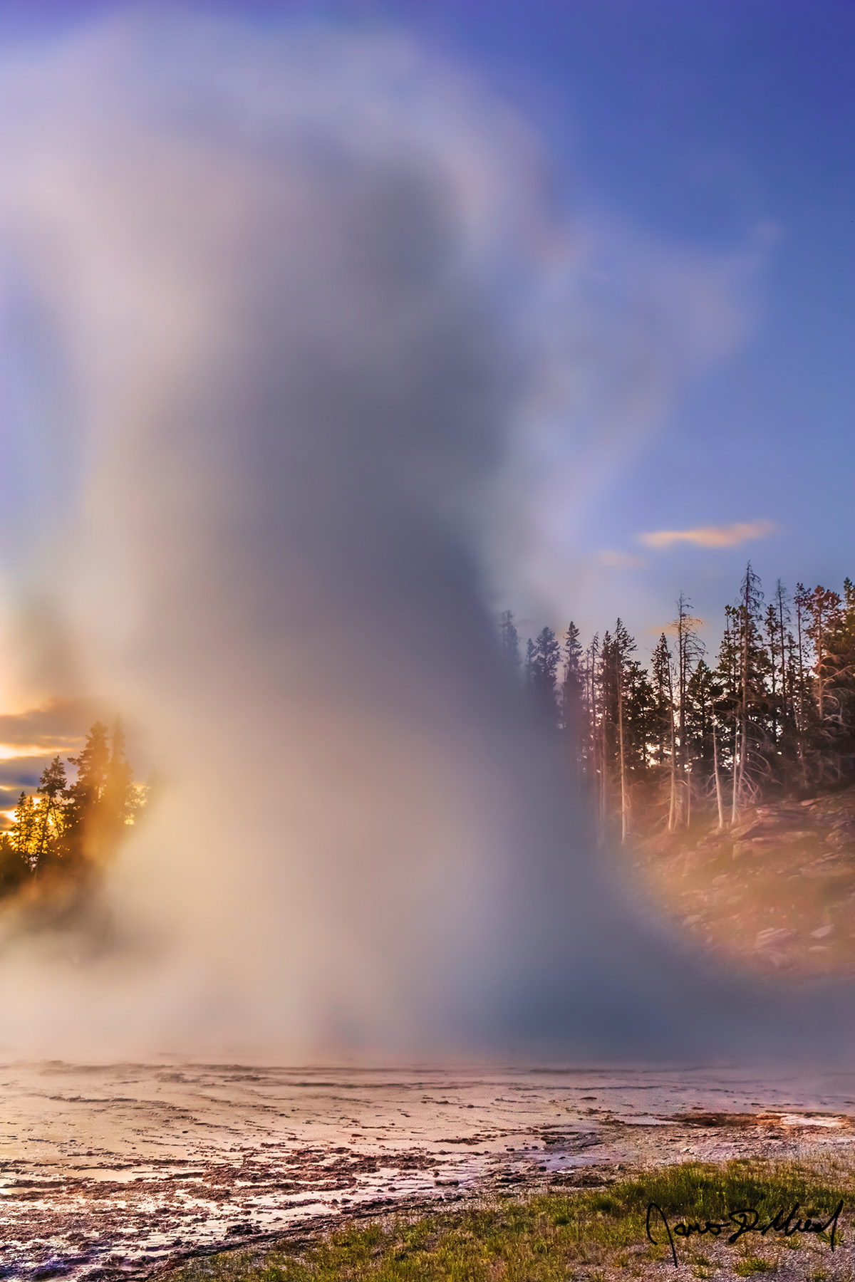 Water Twister Sunset lights the skies above Grand Geyser in Upper Geyser Basin as the light from the setting sun reflects off the water spray as Grand Geyser erupts 200 feet.