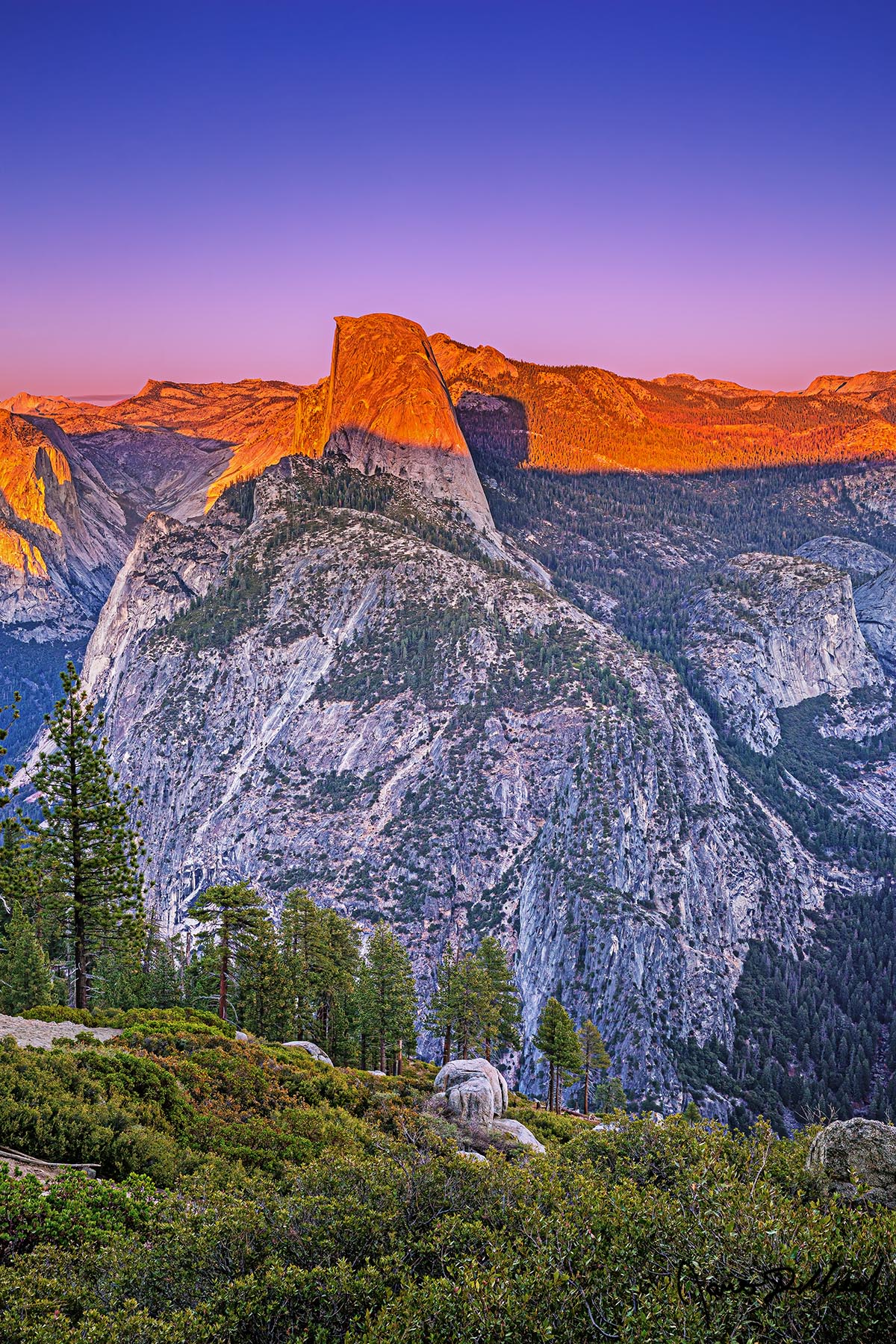 Orange Marmalade Half Dome, Mount Watkins, Clouds Rest, Tenaya Peak, Tressider Peak, Kuna Crest, Fletcher Peak, and the tip of Ahwiyah Point are bathed in alpenglow at sunset.