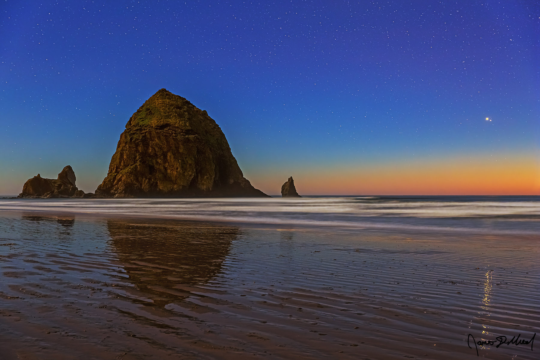 The Great Goodnight The Great Conjunction of Jupiter and Saturn shine brightly in the night sky over Haystack Rock and the Pacific Ocean as it reflects on the thin sheet of water.