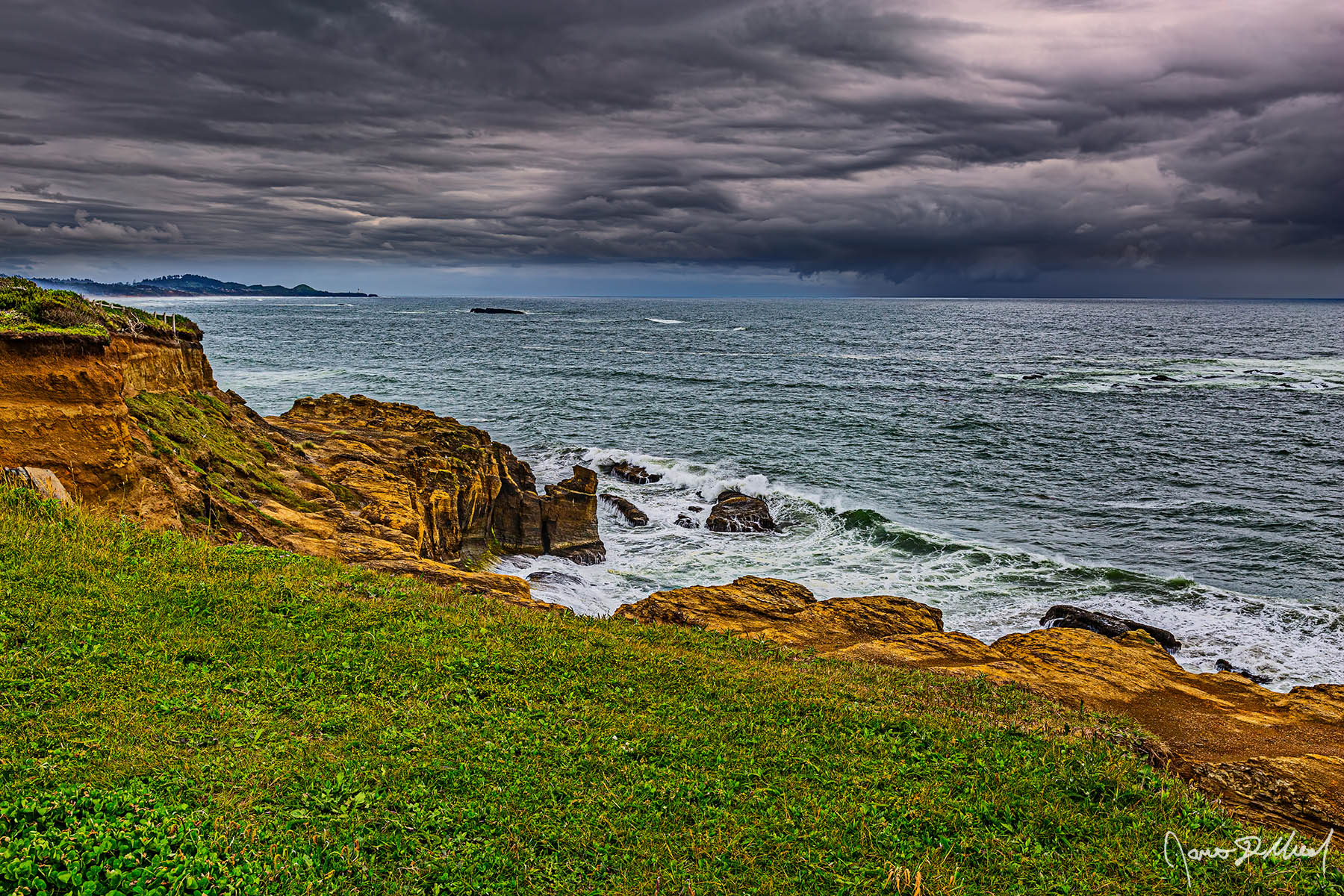 Chaos over the Ocean Storm clouds line the skies above the Pacific Ocean and the sandstone bluffs as Yaquina Head and Yaquina Head Lighthouse jet out into the Ocean in the distance.