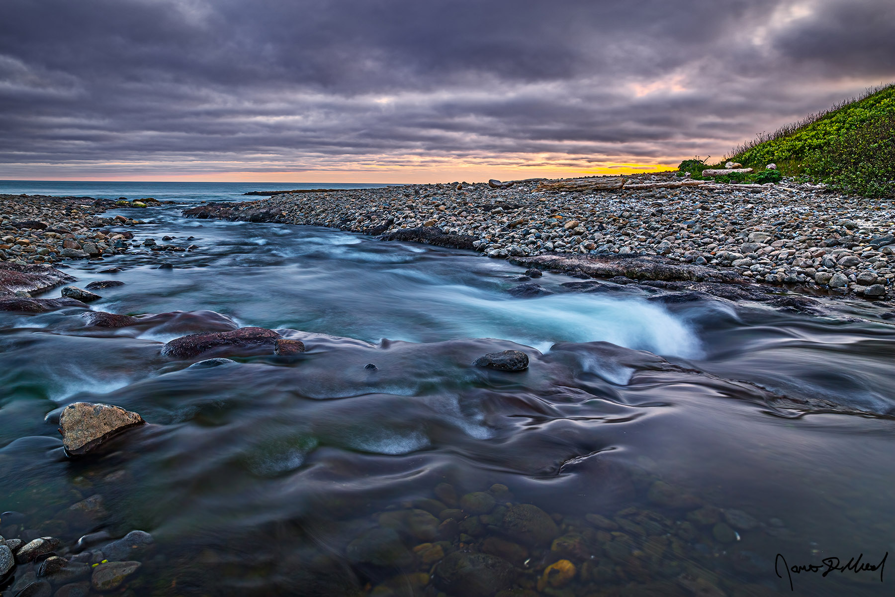 Symphony of Water The colors of sunset peak through breaks in the cloud cover as a fast flowing creek flows directly into the Pacific Ocean along the Oregon Coast.