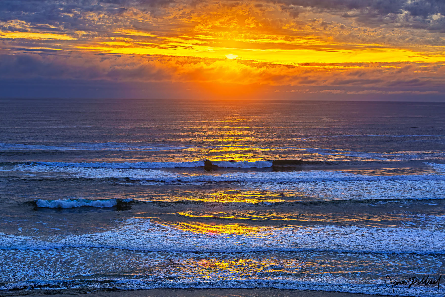 Heaven's Whisper Sunset lights the sky over the Pacific Ocean with color as waves roll in and the sun shines through a break in the clouds.