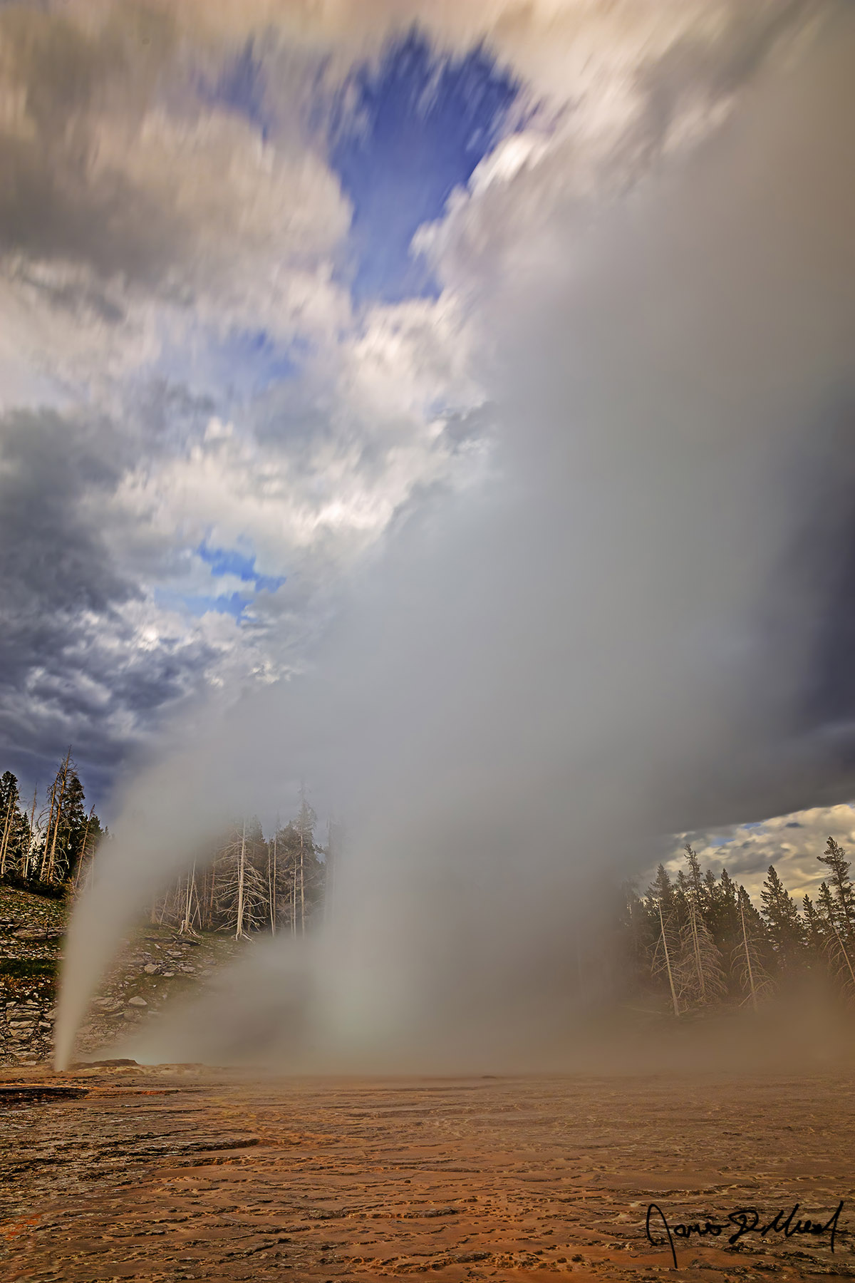 Blast Sunset begin to light storm clouds above as the Grand Geyser Complex erupts. Grand Geyser erupts 200 feet into the air while Vent Geyser erupts 75 feet.