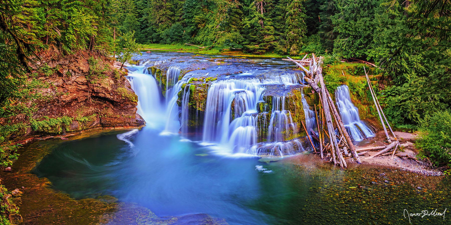 Emerald Pools Water flows over Lower Lewis River Falls, creating a series of small terraces as it flows over the rocky cliffs of the Lewis River and into an emerald pool.