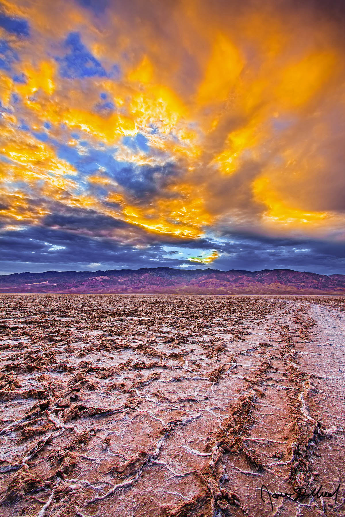 Fire in the Sky - Golden Storm Clouds Sunset over Badwater Basin Salt Formations, Death Valley, CA Sunset bathes the storm clouds above Badwater Basin in Death Valley with brilliant light as the salt formations in the salt flat below stretch as far as the eye